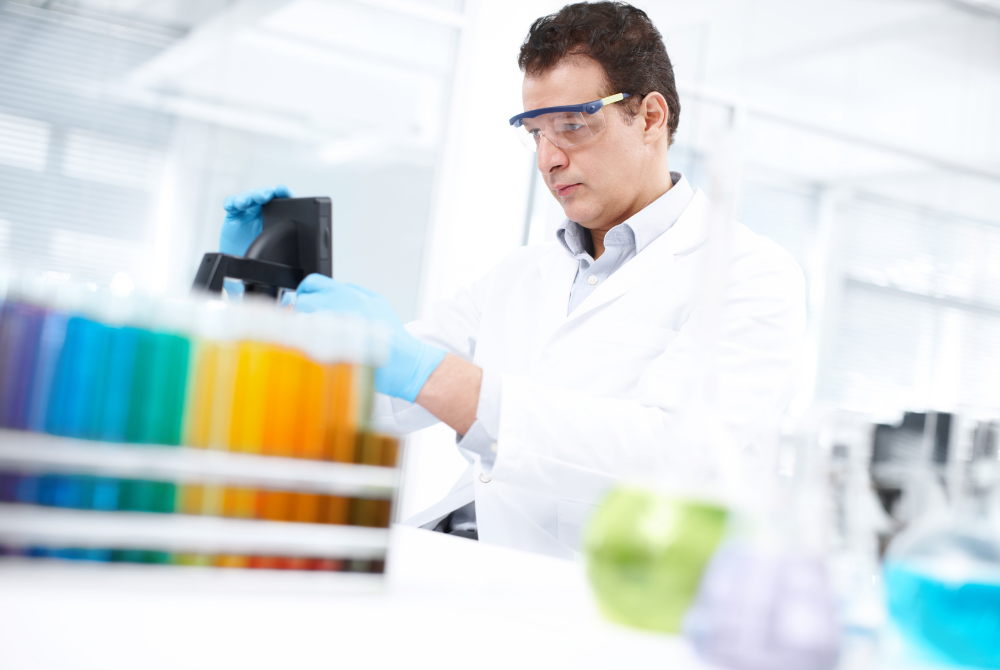 Lab technician conducting tests on lots of colourful liquids in test tubes