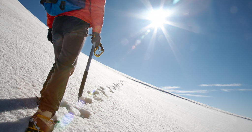 Lone mountain climber on a snowy slope with sun shining brightly and blue skies.  Onwards and upwards for the adhesives specialists market.