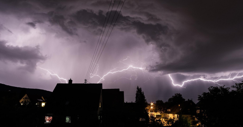 storm clouds and lightening at night above street.  Indicating a stormy yey for the adhesives specialists market.