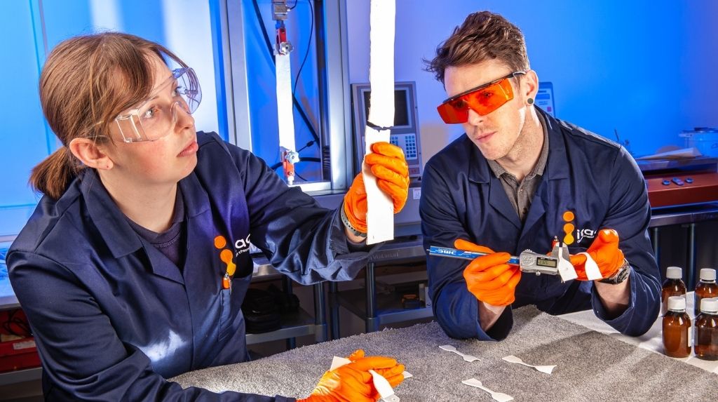 Two development chemists in lab performing tensile test.