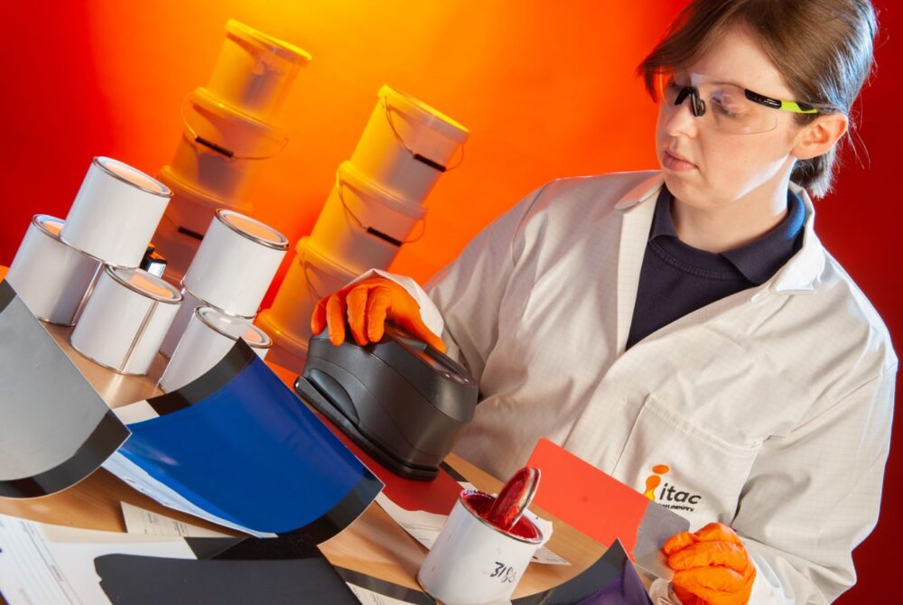 Female laboratory technician in a white overall performing colour testing on coating material.