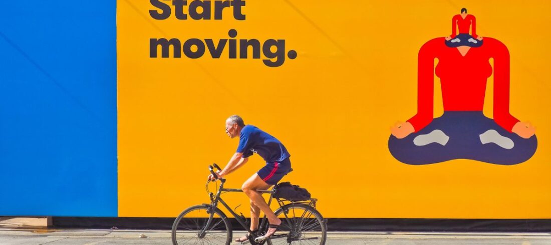 Man cycling past a large poster graphic saying "Keep Moving". Coating used to enhance print colour and clarity.