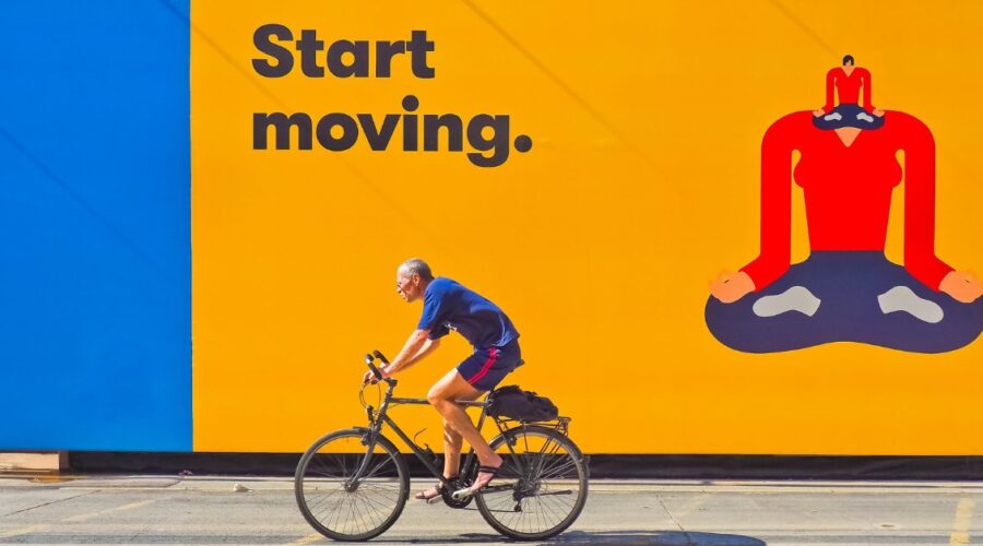 Man cycling past a large poster graphic saying "Keep Moving". Coating used to enhance print colour and clarity.